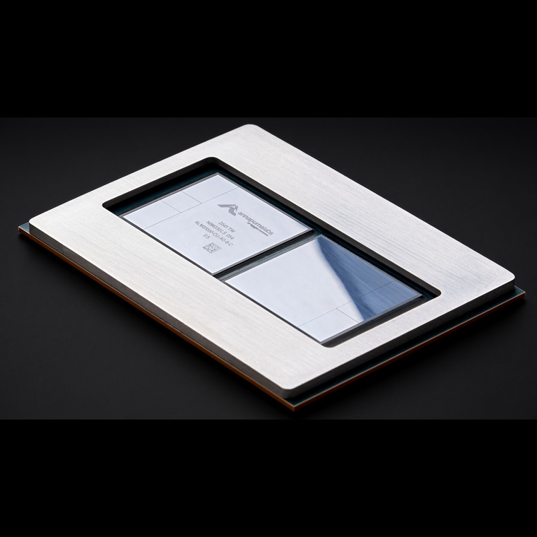 AWS Trainium2 chip package: two silicon compute dies, each flanked by memory stacks, inside a silver frame stamped with the Annapurna Labs logo, on a black background.